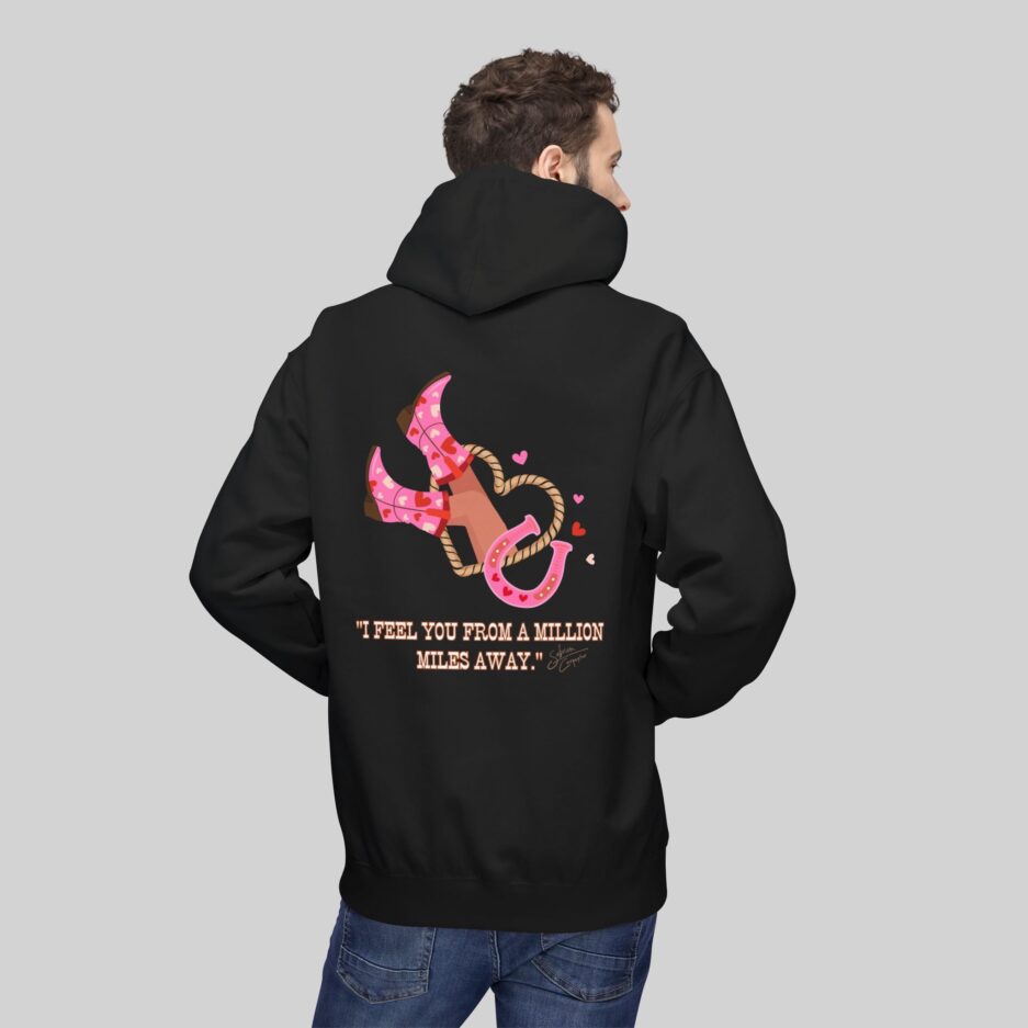 Person wearing a black Sabrina Carpenter Love Club Hoodie with pink design and text on the back against a gray background