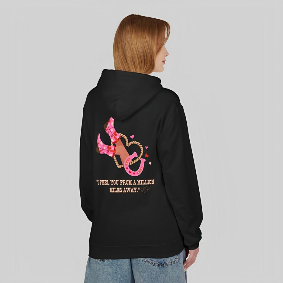 Person wearing a black Sabrina Carpenter Romantic Message Hoodie with a pink anchor design and text on the back, standing against a plain background.